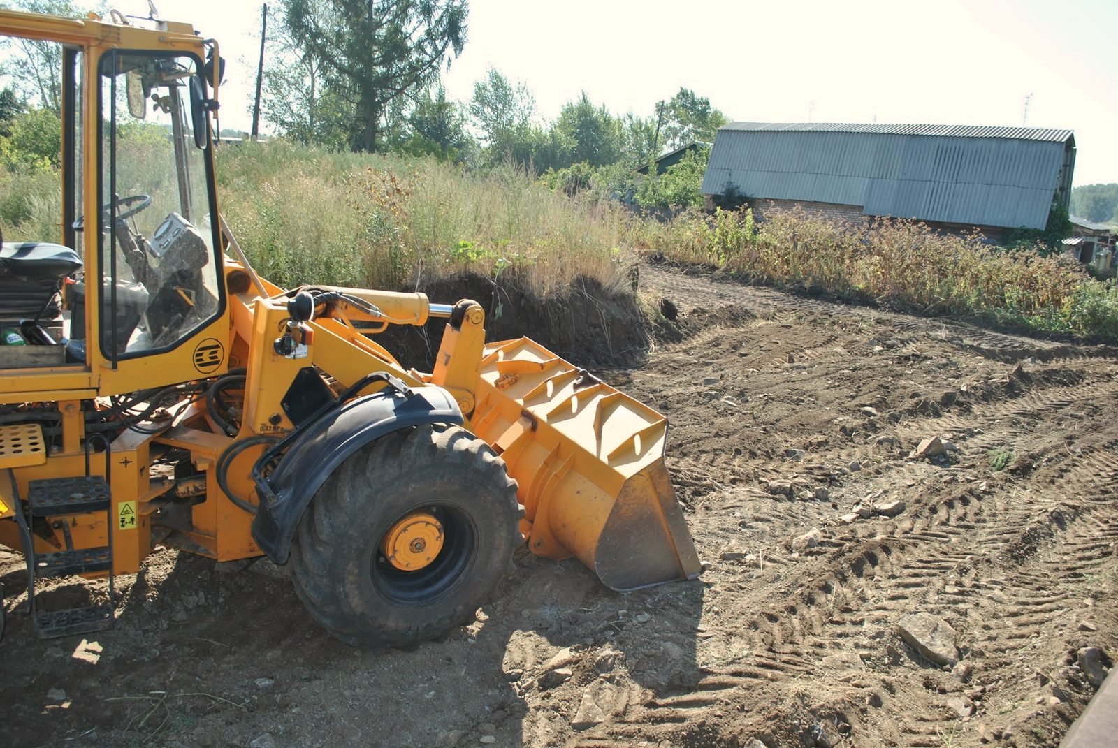 A wheel loader parked on churned ground near a field